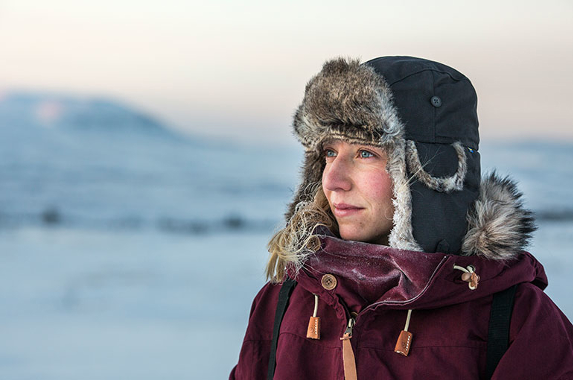 Woman wearing parka and winter hat looking into distance
