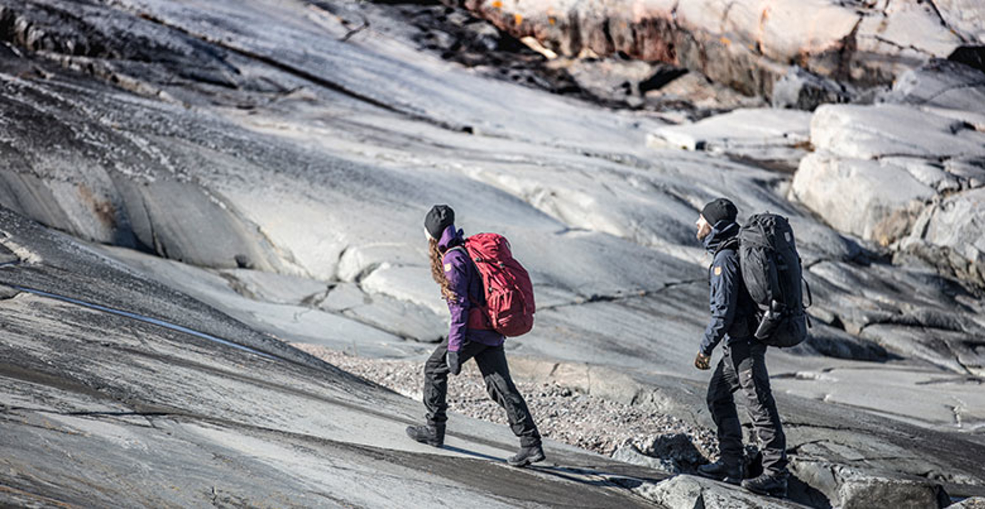 Man and woman walking up rough rock hiking